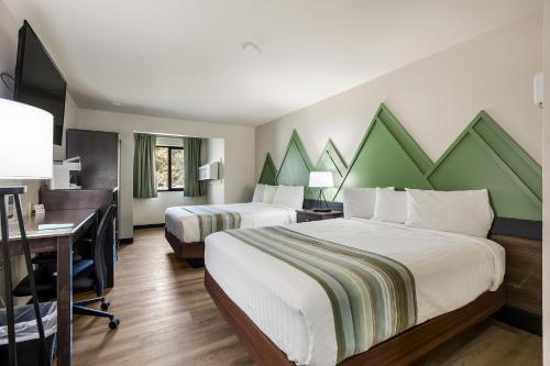 a hotel room with two beds and a desk and a computer at Mountain Vista Hotel in West Yellowstone