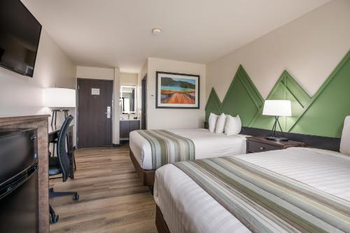 a hotel room with two beds and a flat screen tv at Mountain Vista Hotel in West Yellowstone