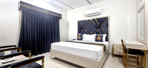 a bedroom with a large bed with a blue curtain at Pakeeza Hotel - Faisal Town in Lahore