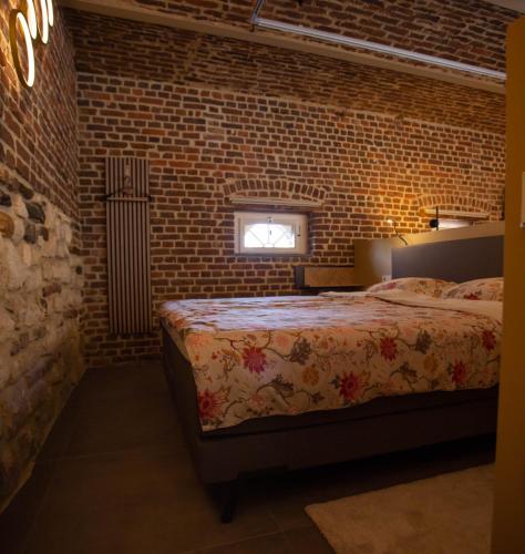 a bedroom with a bed and a brick wall at De Schroer in Wahlwiller
