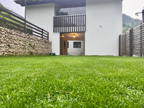 a house with a grassy yard in front of it at Ranger Chalet in Moieciu de Sus