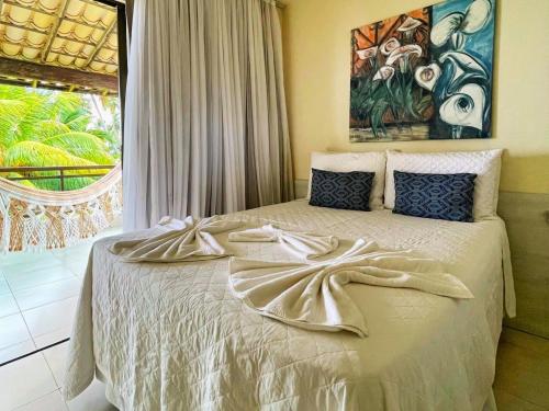 a bedroom with a bed with a painting on the wall at Bangalôs de Peroba in Maragogi