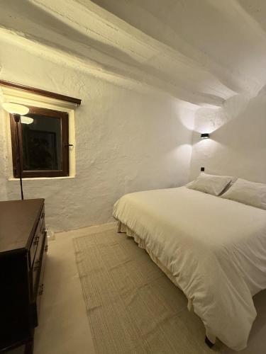 a white bedroom with a bed and a window at Casa Les Ferreres Montblanc in Montblanc