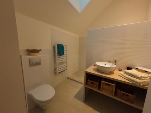 une salle de bain avec des toilettes blanches et un lavabo dans l'établissement la maison bleue, à La Haye-du-Puits