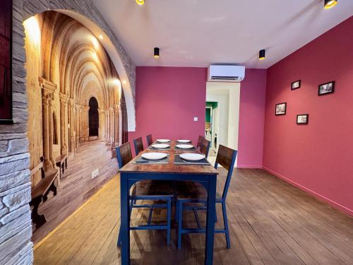 une salle à manger avec une table et un mur rouge dans l'établissement l'instant cathédrale, à Vienne