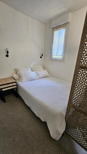 un lit blanc dans une chambre avec une fenêtre dans l'établissement Studio Gare Corte, à Corte