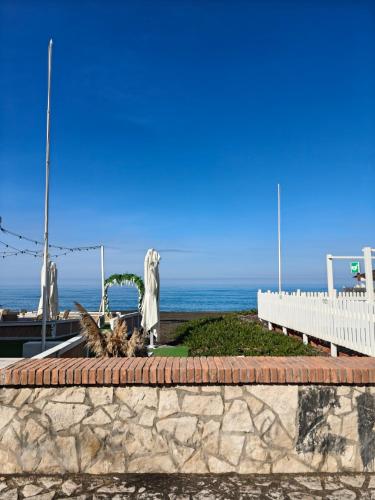 a stone wall with a statue in front of the ocean at Oltremare FRONTE SPIAGGIA in Ladispoli