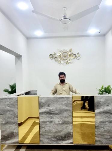a man standing behind a counter in a room at Pakeeza Hotel - Faisal Town in Lahore