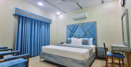 a bedroom with a large bed with blue curtains at Pakeeza Hotel - Faisal Town in Lahore
