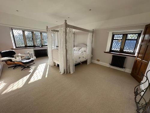 a bedroom with a canopy bed in a room with windows at Greenacres Hall in Disley