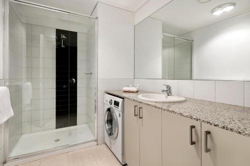 a bathroom with a sink and a washing machine at Quest Jolimont in Melbourne