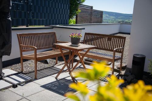 two benches and a table with a potted plant on a patio at WohnRaum Gäste- & Boardinghaus in Gusterath