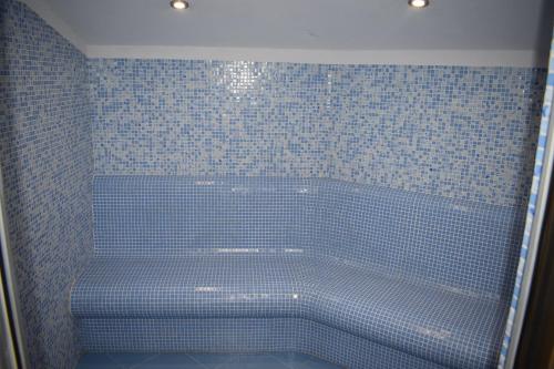 a blue tiled shower with a tub in a bathroom at Constantzia Balneohotel in Kostenets