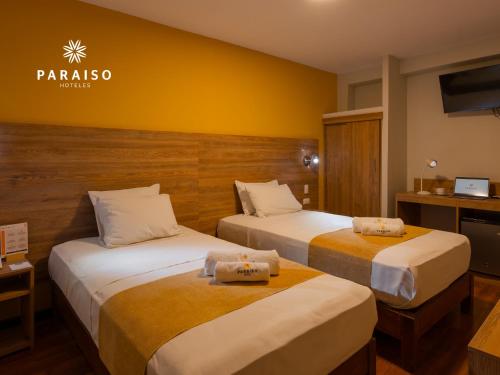 two beds in a hotel room with yellow walls at Hoteles Paraiso CHICLAYO in Chiclayo