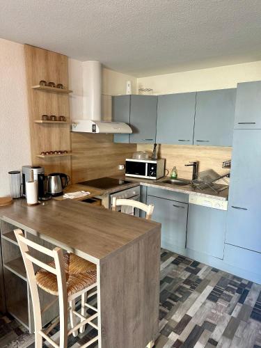 une cuisine avec des armoires bleues et un comptoir avec des chaises dans l'établissement Appartement à 6 minutes à pied de la mer, à Cagnes-sur-Mer