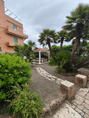 a garden with palm trees and a building at Oltremare FRONTE SPIAGGIA in Ladispoli