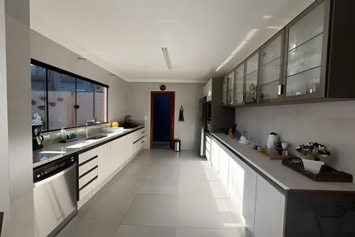 a large kitchen with white counters and a blue door at Casa da Tribo Hospedagem in Bom Jardim da Serra