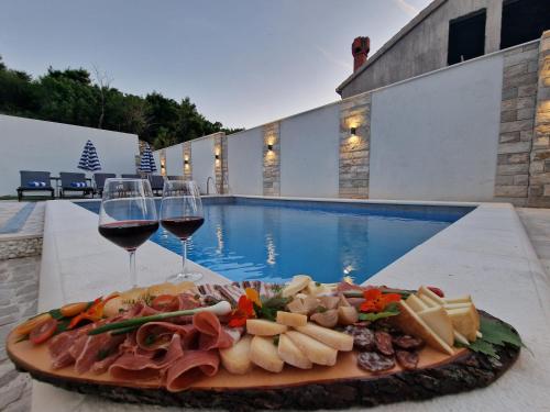 a plate of food and wine glasses next to a pool at Apartment Casa Lumina - 5 minutes to the airport and centar all private in Zvekovica