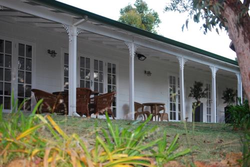 a white house with rocking chairs on the porch at Llewellin's Guest House in Margaret River Town