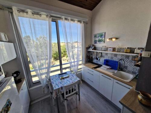 une cuisine avec des placards blancs et une grande fenêtre dans l'établissement Résidence Tennis 2 - APPT T2 MEZZ 4 couchages PORT LEUCATE MAE-5854, à Port-Leucate