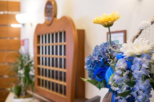a vase filled with blue and white flowers next to a mirror at Residence Queen in Rimini
