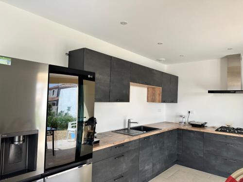 une cuisine avec des armoires grises et un évier dans l'établissement Maison familiale avec piscine près de Nimes Calme & confort en Provence, à Saint-Gilles