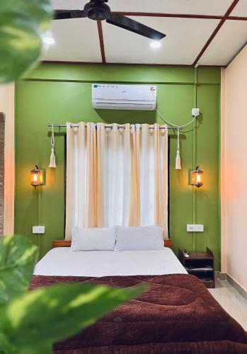 a bedroom with a bed and a green wall at Dee Bohemian Stay in Jorhat