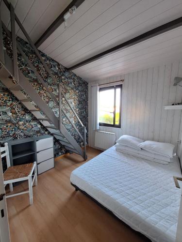 une chambre avec un grand lit et un escalier dans l'établissement Charmante maison de vacances proche plage Saint Hilaire de Riez, Vendée, à Saint-Hilaire-de-Riez