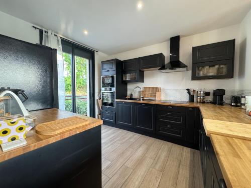une cuisine avec des armoires noires et des comptoirs en bois dans l'établissement LUrbanMans - Circuit Bugatti - Wi-fi, au Mans