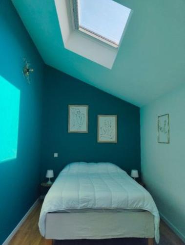 une chambre avec un lit avec un mur bleu dans l'établissement Jolie maison brévinoise, à Saint-Brévin-les-Pins