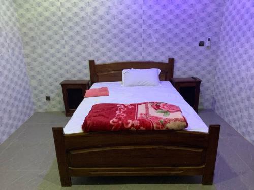 a bedroom with a wooden bed with a red blanket at Villa Malya-Rez de chaussée Privé et indépendant avec deux chambres et jacuzzi dans une maison- in Saly Portudal