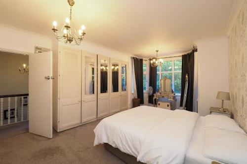 a bedroom with a large white bed and a chandelier at Westmorland - 4 Bedroom House - FREE Parking for up to 7 Cars - Walking distance to QMC and University - Ideal for Contractors and Large Groups in Nottingham