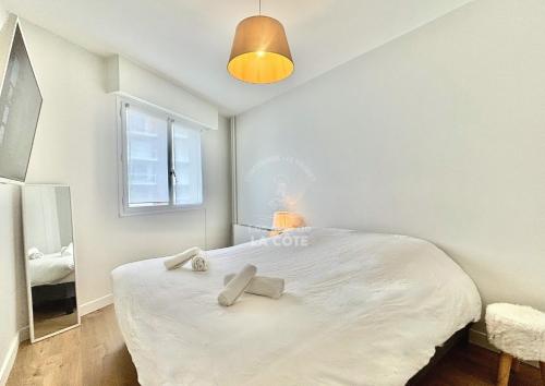 une chambre avec un grand lit blanc avec une fenêtre dans l'établissement Le Bedford, à Le Touquet-Paris-Plage