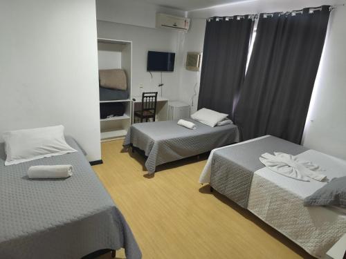 a hotel room with two beds and a chair at Hotel Colonial in Irati