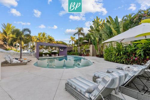 a swimming pool with lounge chairs and an umbrella at QUIYA - Luxury Condos with Exclusive Beach Club in Cruz de Huanacaxtle