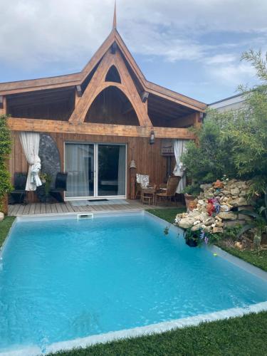 - une piscine en face d'une maison avec une église dans l'établissement Chalet Atypique VUE Piscine Chauffée, à Gujan-Mestras