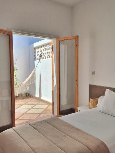 a bedroom with a bed and an open door to a balcony at Hotel Villa Soleil in Sidi Kaouki