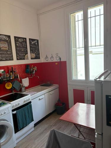 Il comprend une cuisine dotée d'une cuisinière blanche et d'un mur rouge. dans l'établissement Studio spacieux - Centre de Nice, proche mer & gare, à Nice
