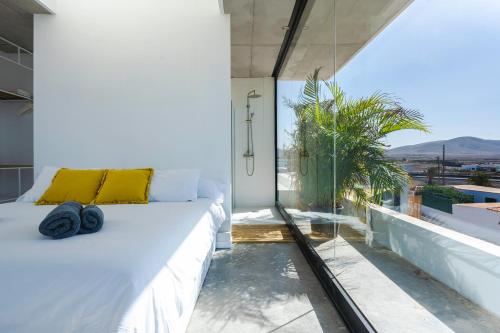 a bedroom with a white bed and a large glass window at Salty Villa by Aura Collection in El Roque