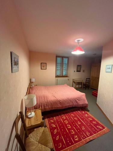 - une chambre avec un lit et un tapis rouge dans l'établissement Maison confort à Rochejean, à Rochejean
