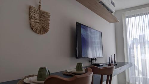 a room with a table and a tv on a wall at Vert House Jardim Oceania - Miramar Hospedagens in Tambaú