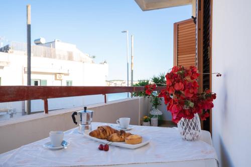 a table with a plate of pastries and a vase of flowers at Tra Cielo e Mare in Otranto