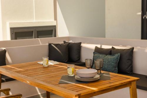 a wooden table with plates and glasses on it at KALIMERA Luxurious Villas in Lixouri