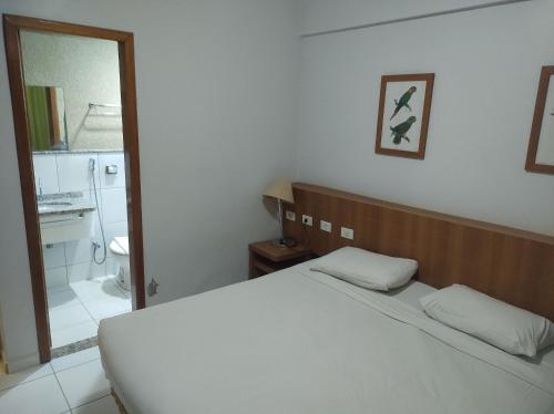 een slaapkamer met een wit bed en een badkamer bij flat 2 qtos Golden Dolphin Roberto Imoveis in Caldas Novas