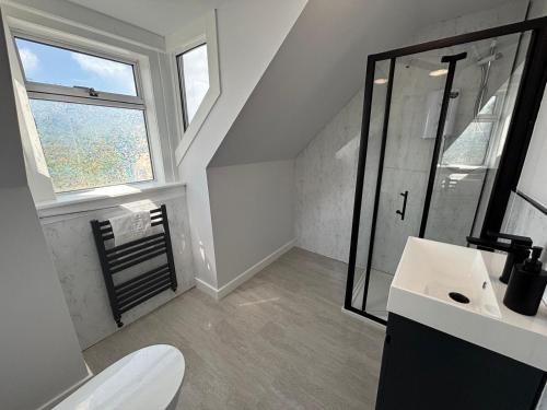 a bathroom with a toilet and a sink and a window at The Hebridean - Rooms & Apartments in Broadford