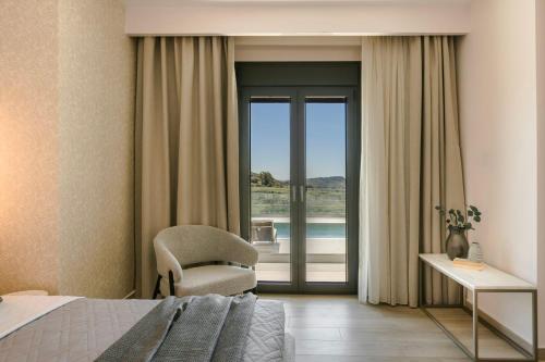 a bedroom with a bed and a chair and a window at KALIMERA Luxurious Villas in Lixouri
