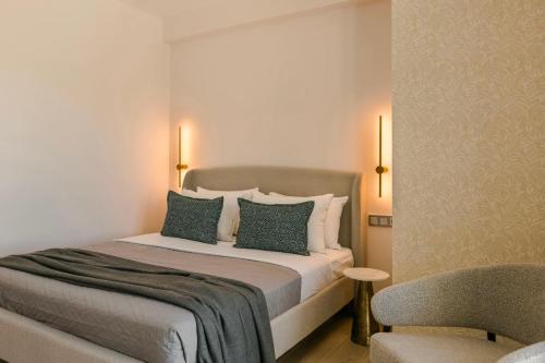 a bedroom with a bed with two pillows and a chair at KALIMERA Luxurious Villas in Lixouri