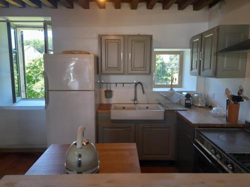 une cuisine avec un réfrigérateur blanc et un évier dans l'établissement Maison DU VERGER, à Quarré-les-Tombes