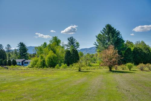 a field with trees and a house in the background at Peaceful and Private Franconia Home by Cannon! in Franconia