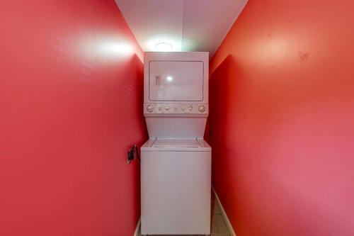 a small white refrigerator in a red room with a light at 11 Mi to Oneida Lake Spacious Apt in Verona! in Verona